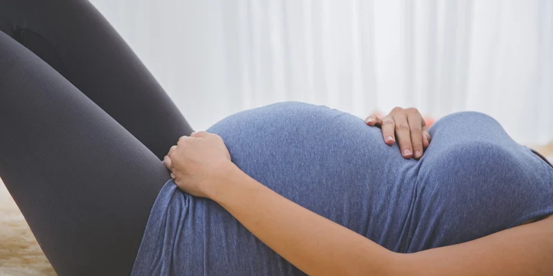 Donna in gravidanza distesa che si accarezza la pancia