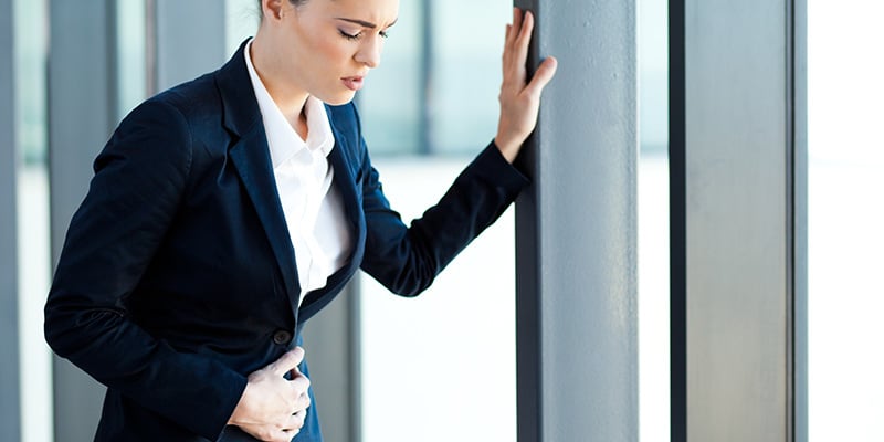 Donna che si tocca la pancia con la mano poggiata sulla porta