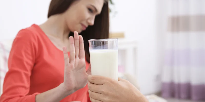Dettaglio di mano femminile che respinge un bicchiere di latte