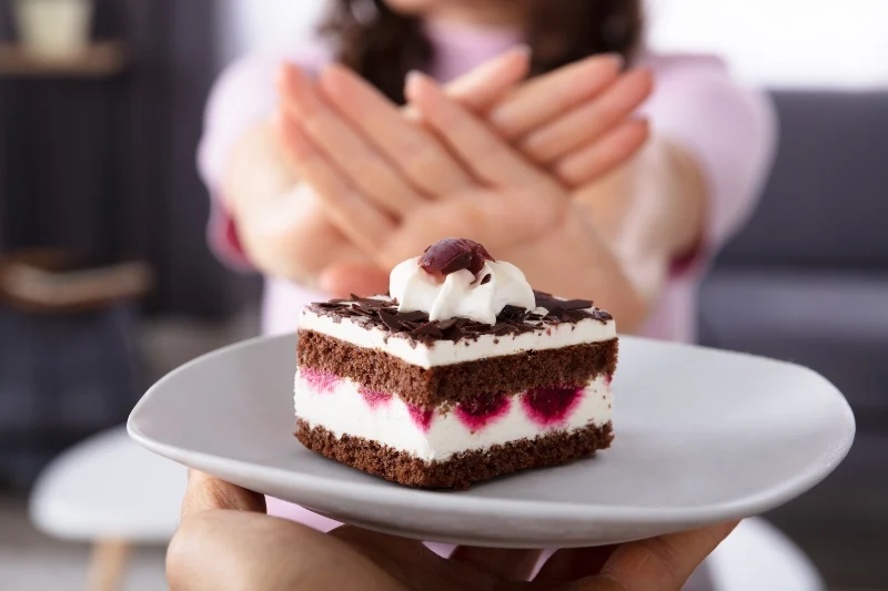 Dettaglio di due mani femminili che respingono una torta al cioccolato