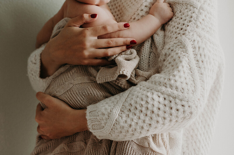 Donna che stringe tra le sue braccia un bambino avvolto in una coperta di lana