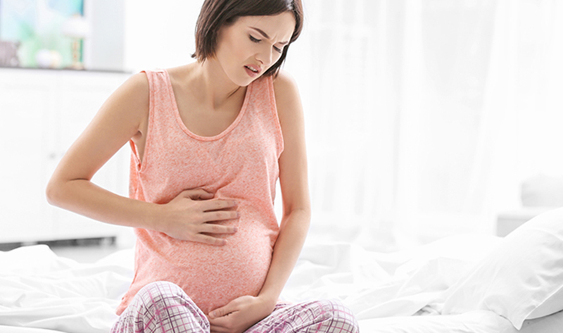Donna in gravidanza con mano sulla pancia - dolori stipsi