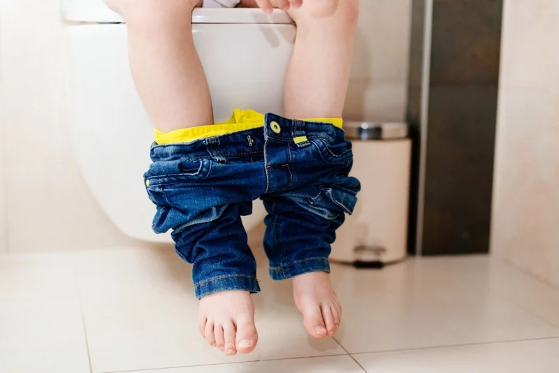 Dettaglio di gambe di un bambino seduto sul WC